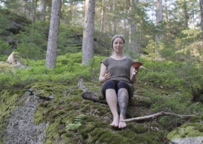 Biologin und Wildkraeuterexpertin Gerda Holzmann sitzt auf dem Waldviertler Waldboden mit einer Raeucherschale aus Ton.